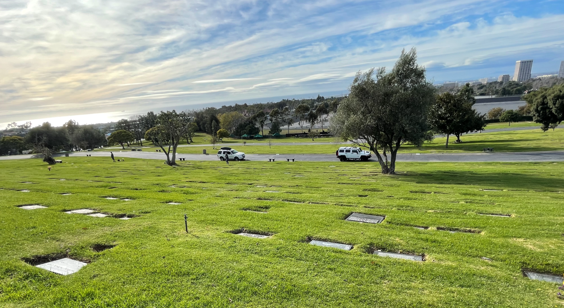 A cemetery with a white van parked in the grass.